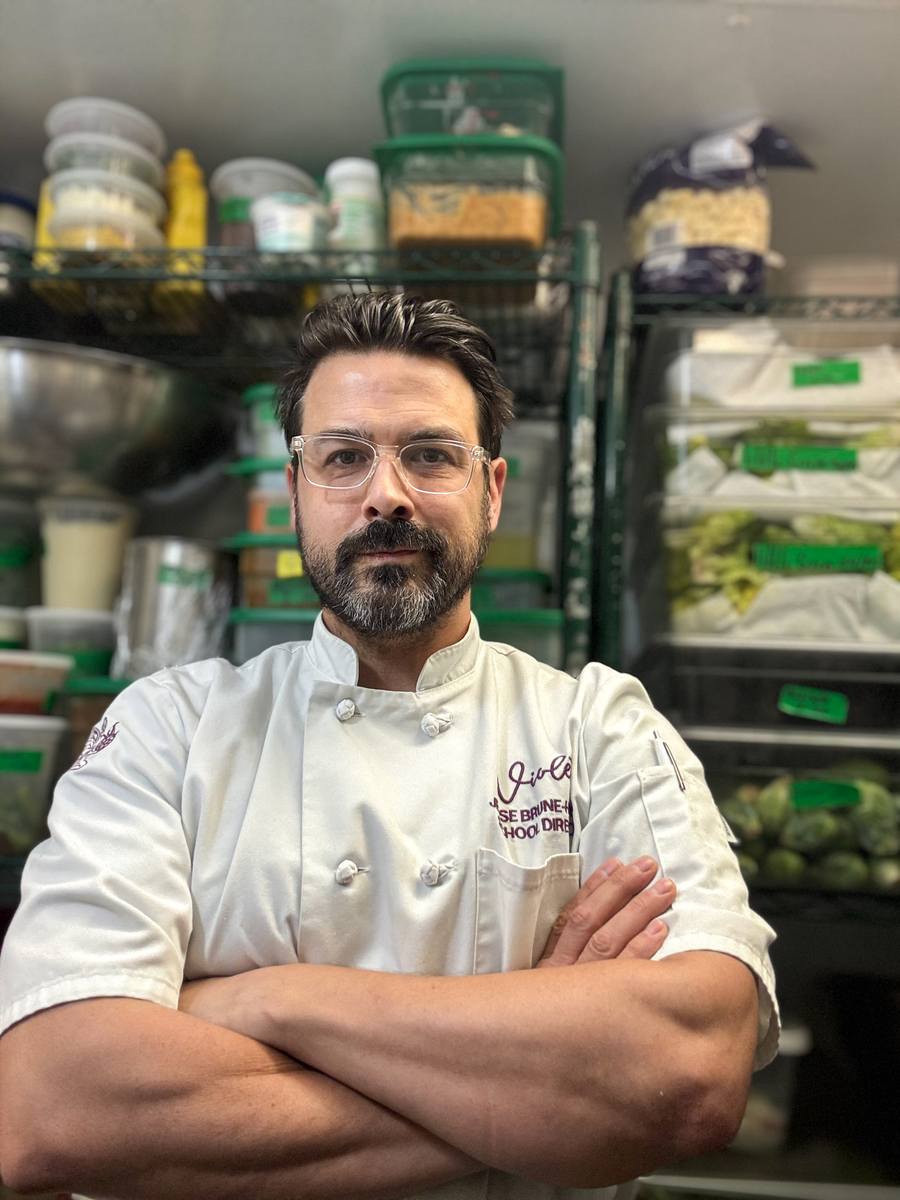 Jesse Brune in chef whites, arms folded, in the walk-in at Violet.