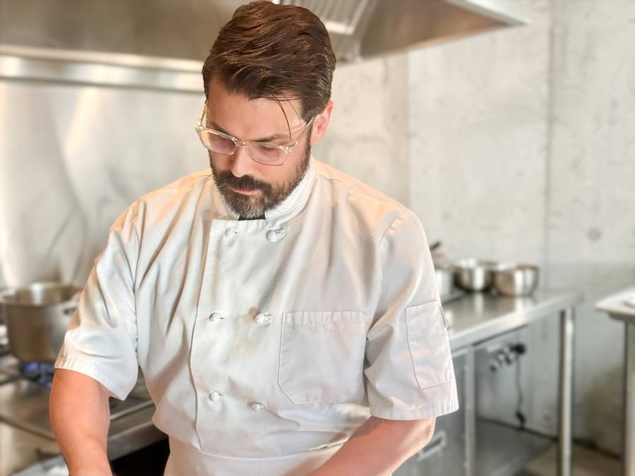 Jesse Brune in chef whites at work in a professional kitchen.