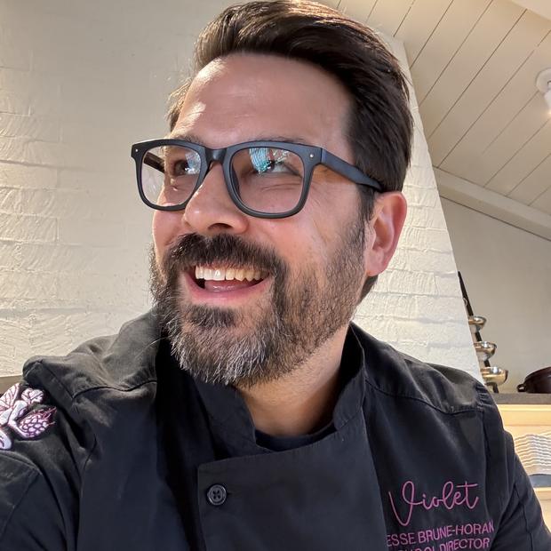 Jesse Brune smiling in a black Violet chef jacket.